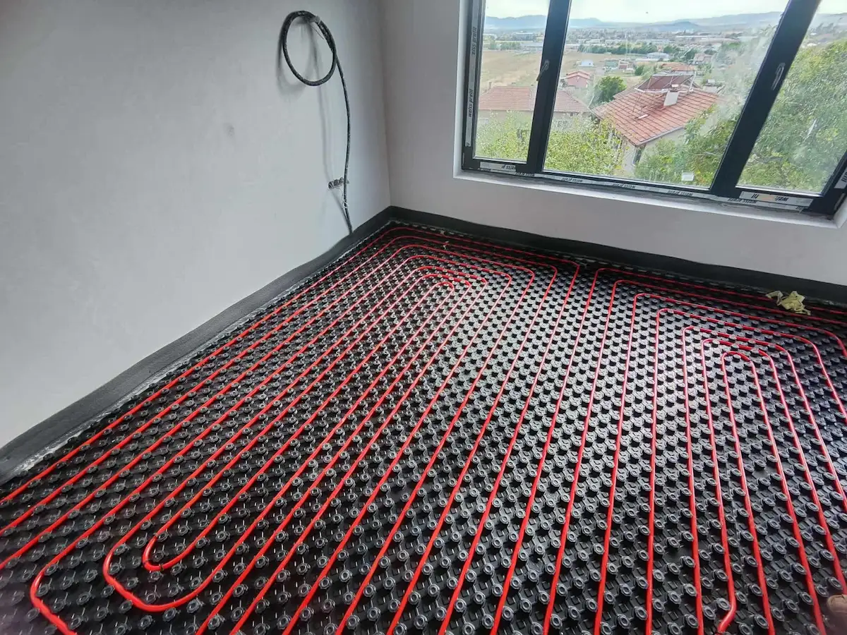 Инсталация на тръби за подово отопление върху черна подложка.